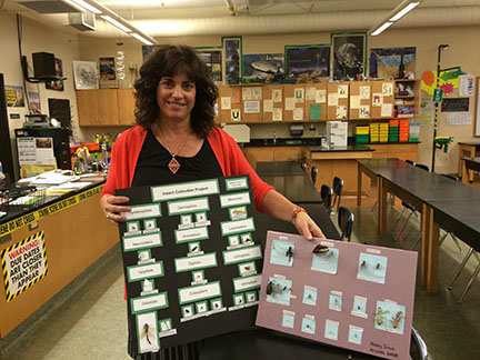 Science teacher Barbie Miller holding two of her students insect collection projects. Kids are learning in a hands on way how biologists classify things.