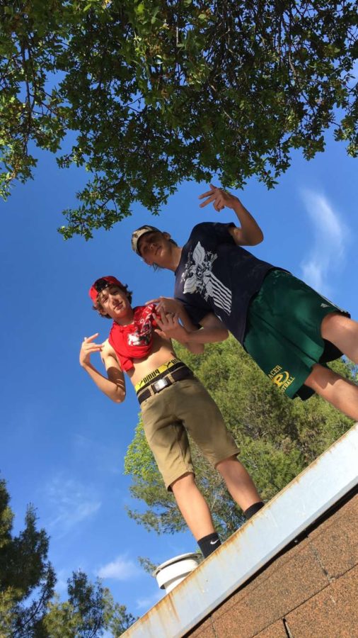 Jared Gaches (left) and Trevor Keller (right) standing on a wall facing the sky.